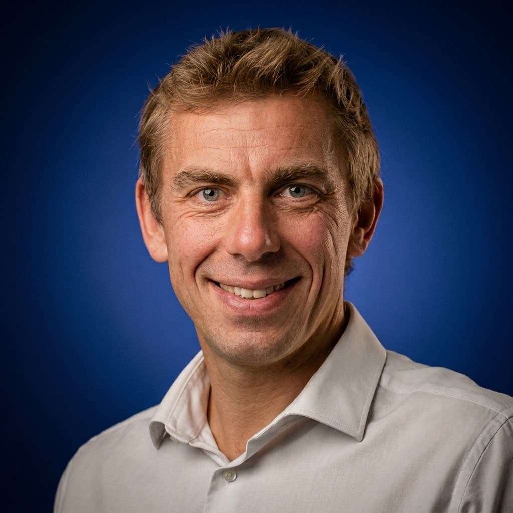 Seb Troz, smiling, light shirt, cobalt studio background